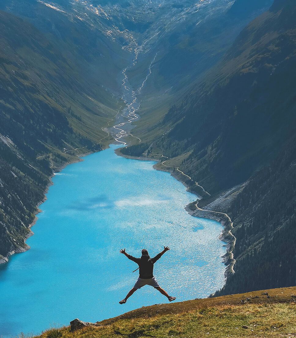 persona saltando lago montañas